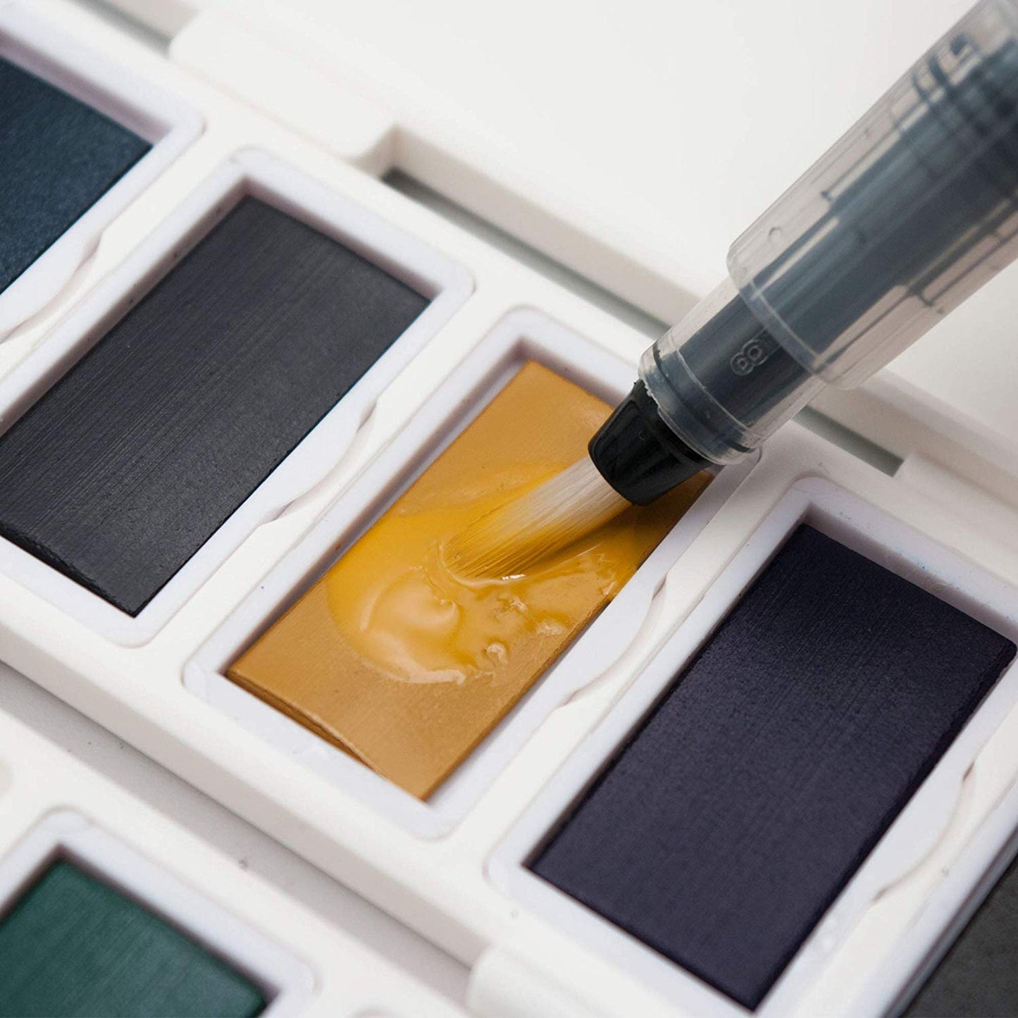 The aqua brush from the Pencilmarch watercolour paint travel set with 38 colours, placed on a paint colour to use - Stationery Island